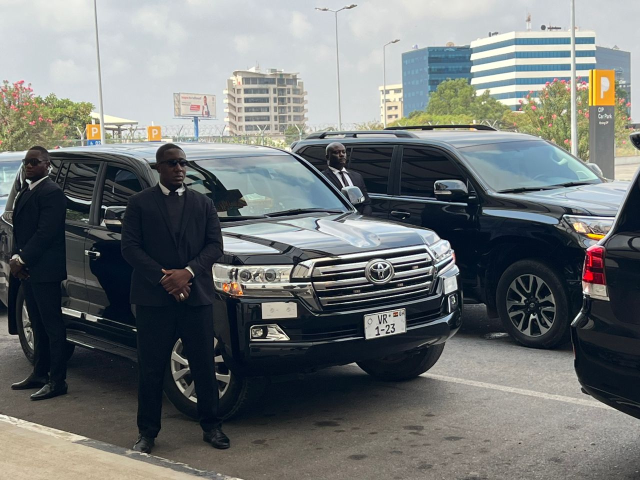 bodyguard in sunglasses opening car door to businessman
